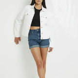 Women wearing white denim trucker jacket leaning against wall - relaxed casual streetwear style