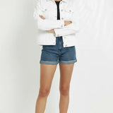White cotton denim jacket for women showing fit and style with arms crossed - button front trucker jacket