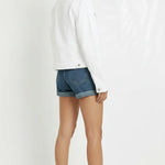 Side and back angle of women's white denim trucker jacket showing silhouette and cuffed sleeves