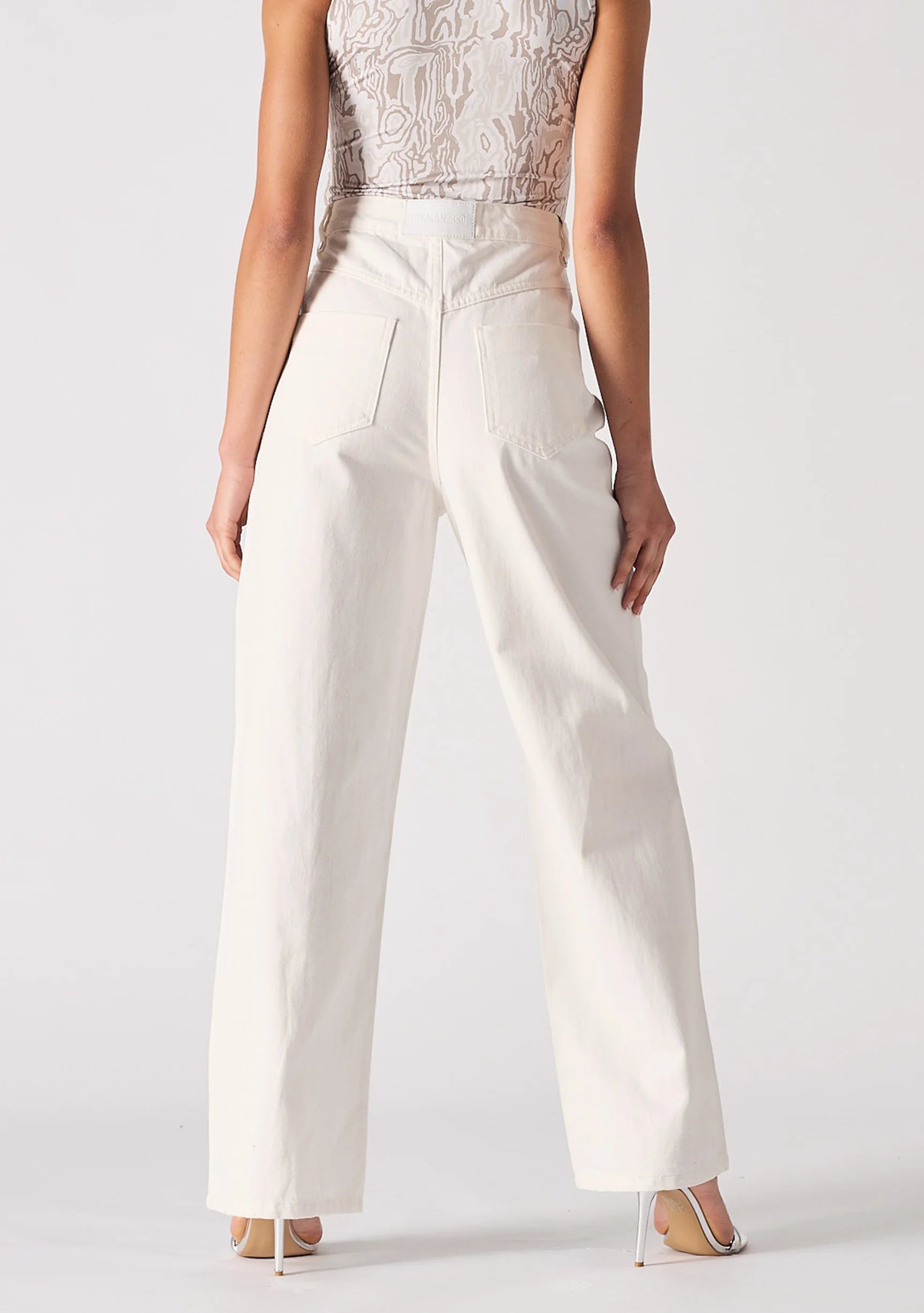 Rear view of white denim jeans highlighting back pocket placement and high-waist fit.