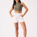 A front view of a woman wearing white jogger shorts with a khaki top