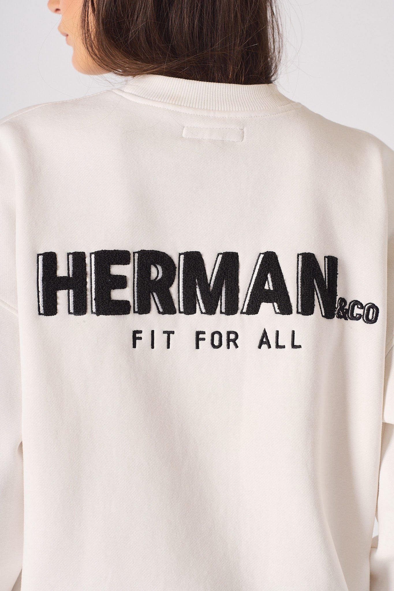 Close up of the black printed text on the back of a white sweatshirt for women