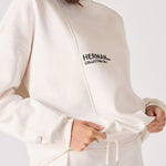 A woman holding the bottom hem of a white sweatshirt for women