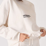 A woman holding the bottom hem of a white sweatshirt for women