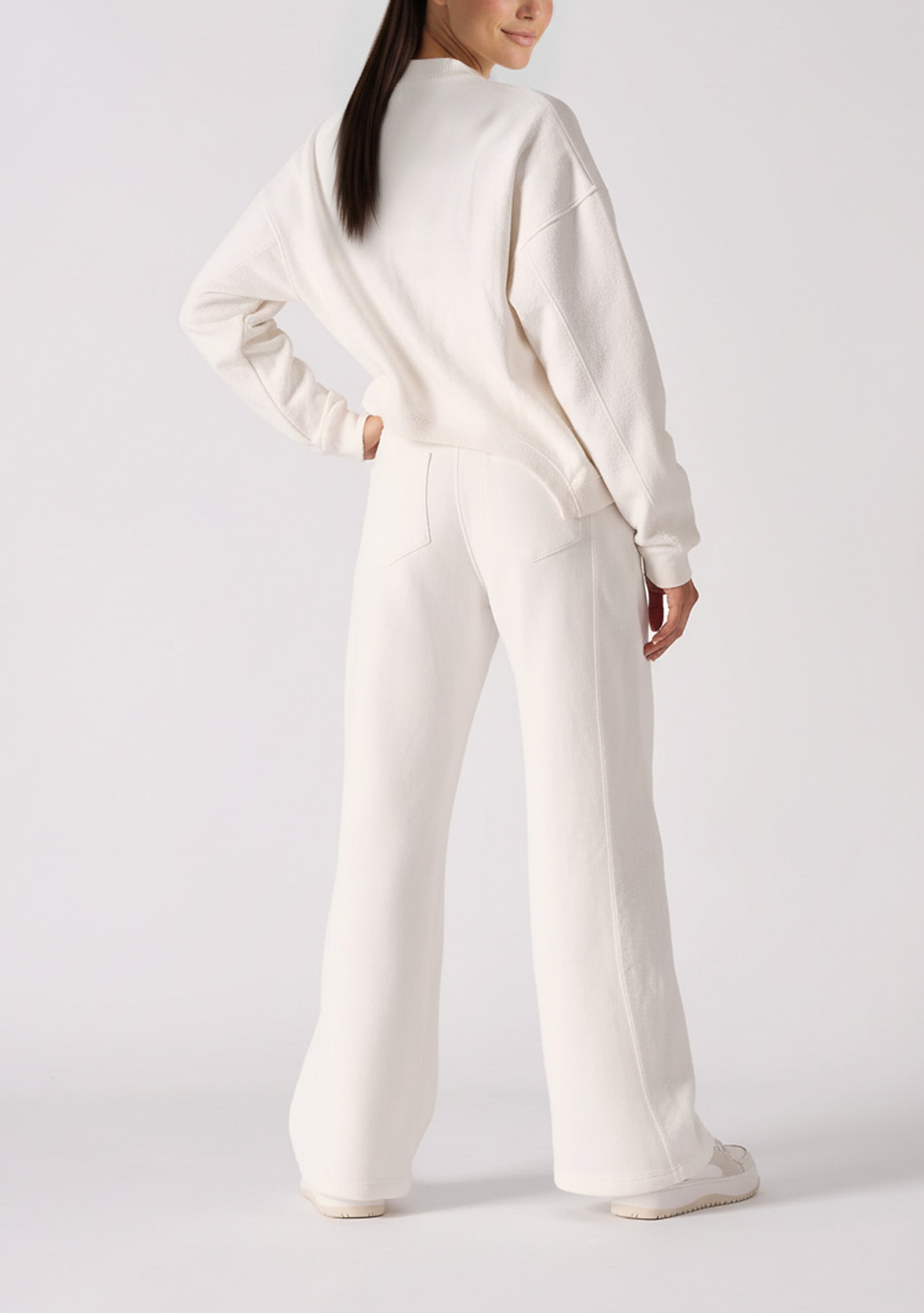 Rear view showing the clean fit of the white wide leg joggers.