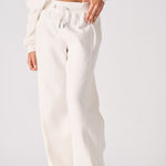 A woman wearing stylish white wide leg joggers in a front pose.