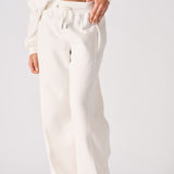 A woman wearing stylish white wide leg joggers in a front pose.