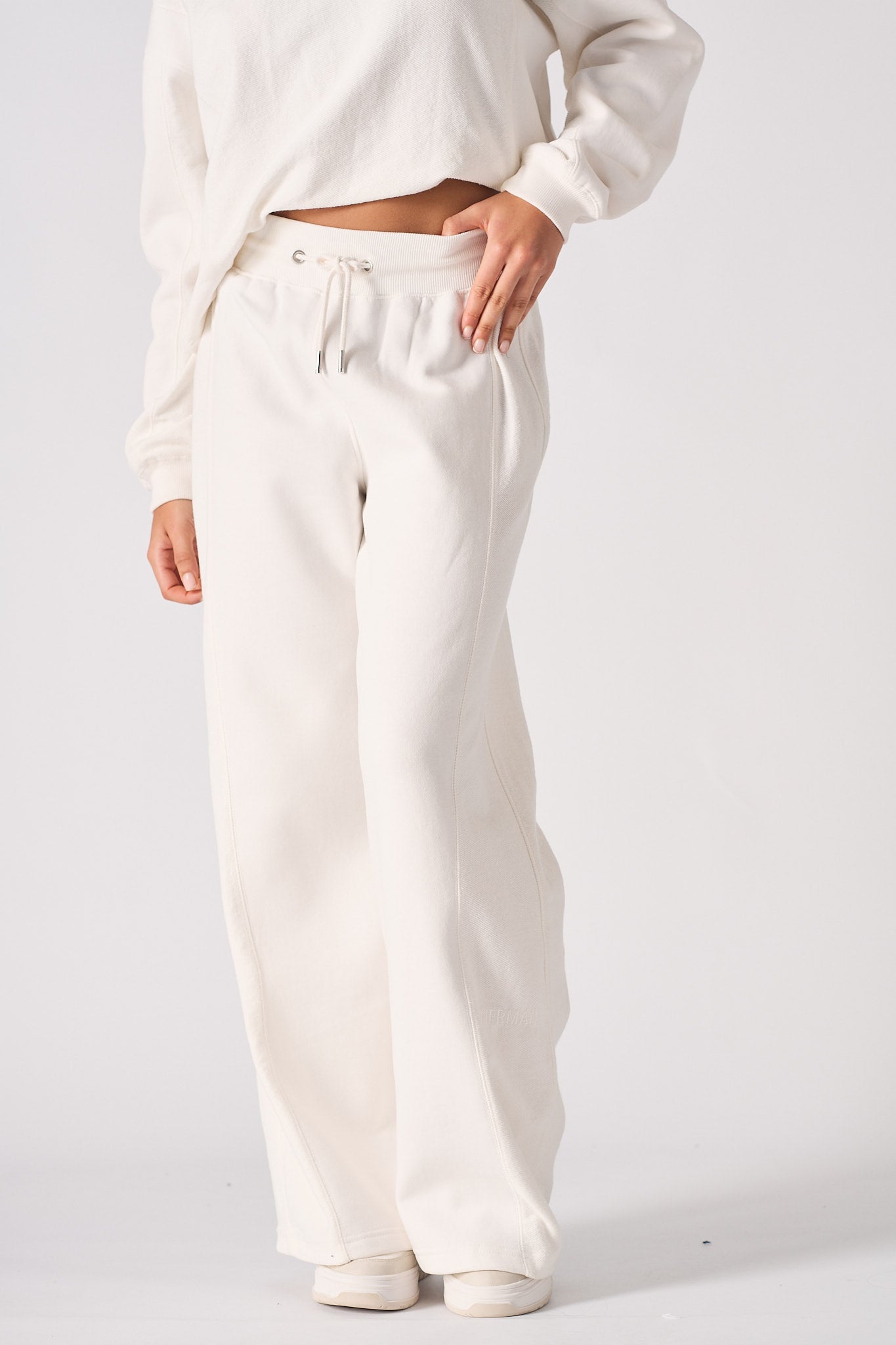 A woman wearing stylish white wide leg joggers in a front pose.