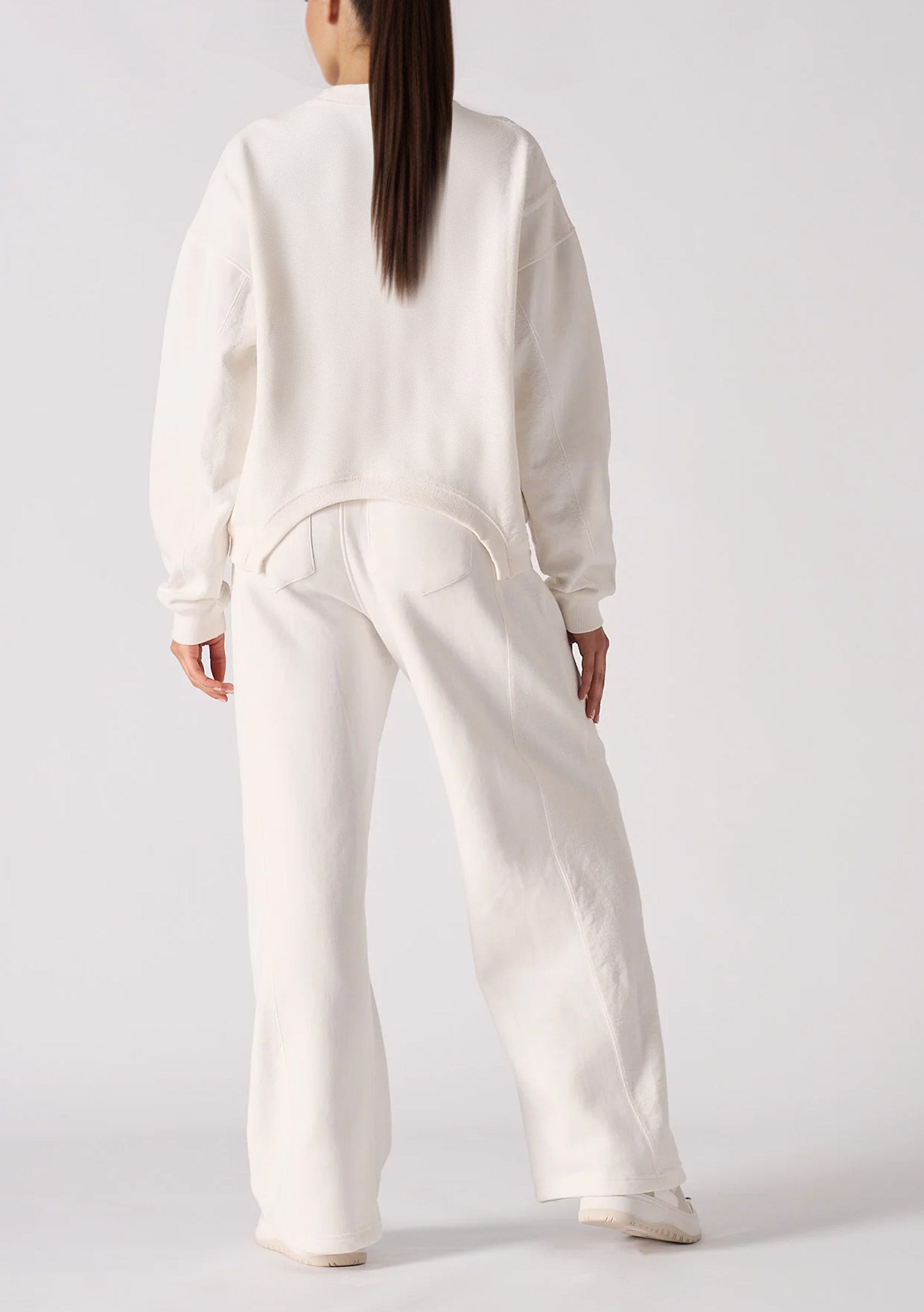 Back view of a model in white wide leg joggers and a matching top.