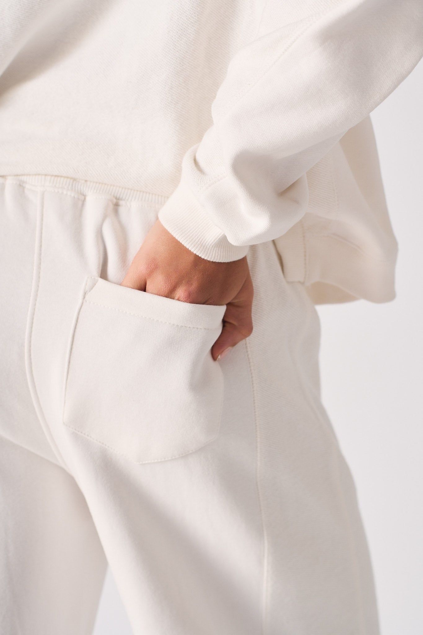 Detailed close up of the back pocket on white wide leg joggers.