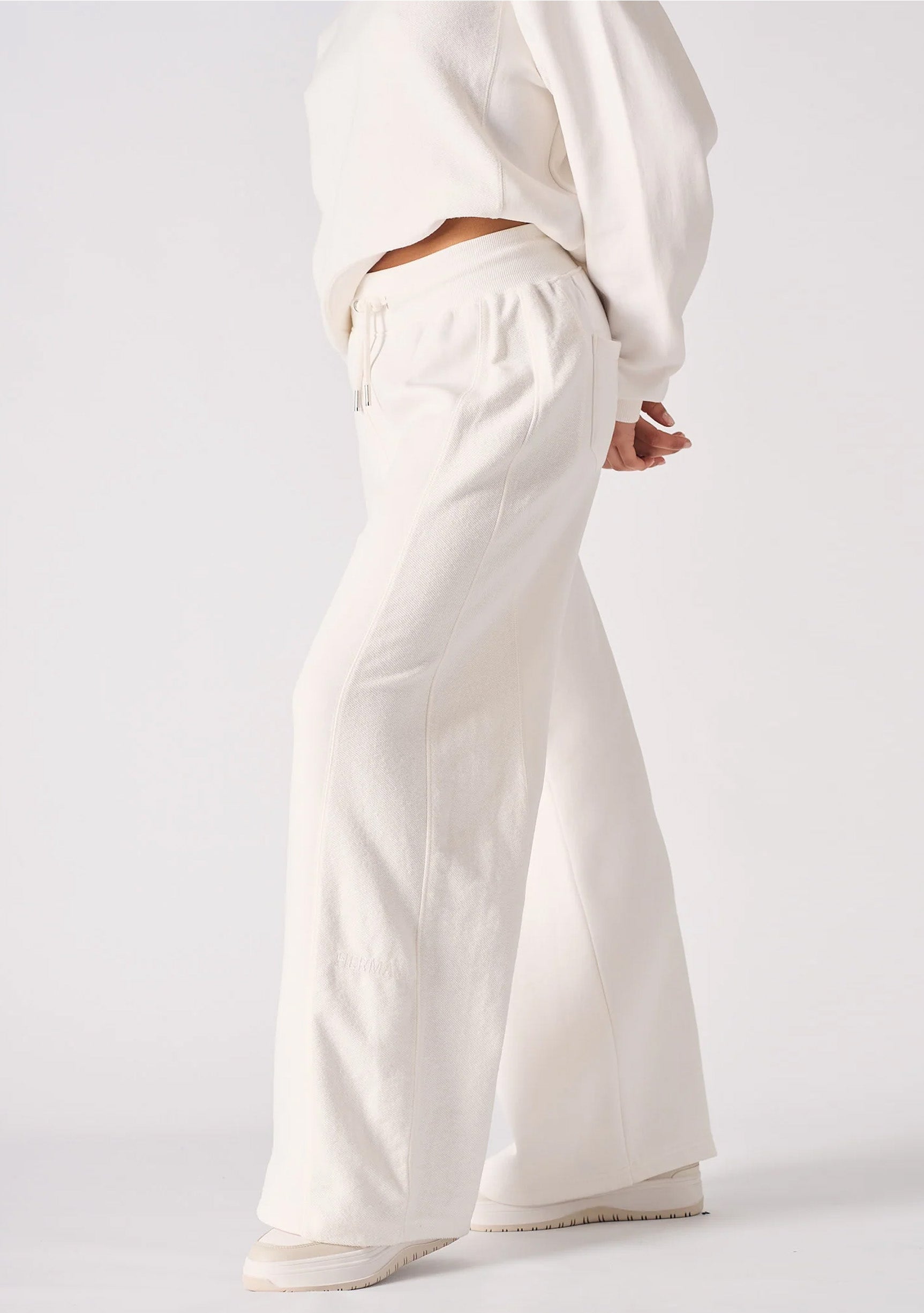 Side profile of a model wearing comfortable white wide leg joggers.