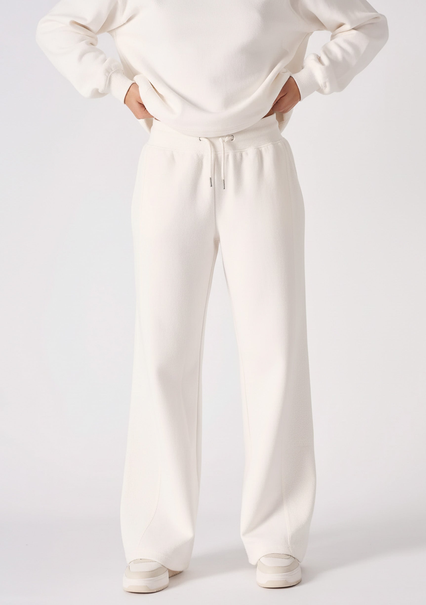 Full body shot of a woman in premium white wide leg joggers.