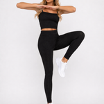 A woman in womens-black-bubble-texture-leggings lifting one knee with arms extended showing full range of movement