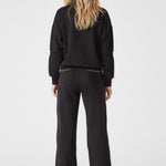 Full back view of a woman wearing a black sweatshirt and joggers set