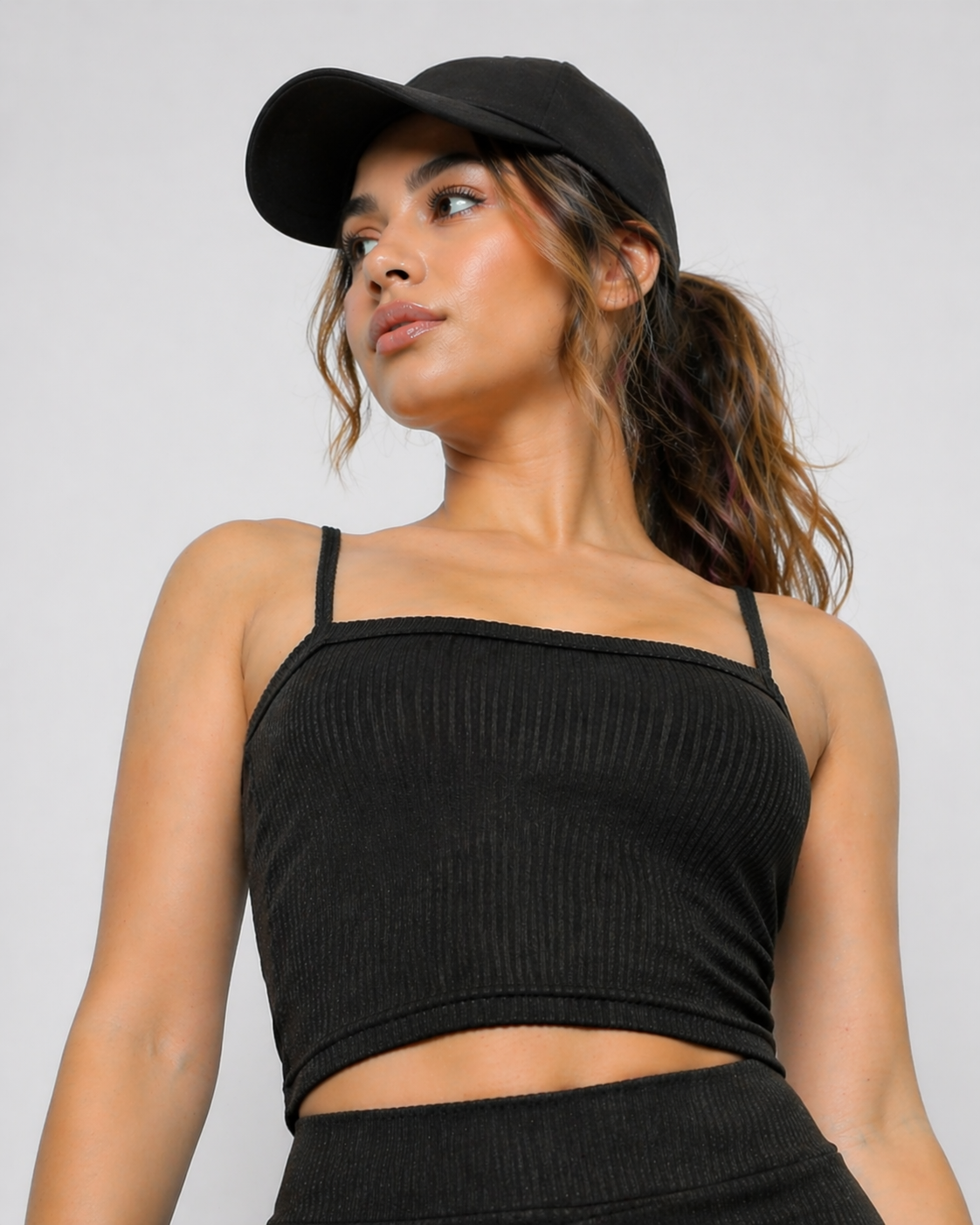 A woman wearing womens-black-ribbed-crop-top standing view showing the cropped length and fitted body skimming fit