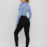 A woman wearing womens-black-high-waist-leggings with a deep waistband, showing the back fit and shape, paired with a blue crop top