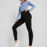 A woman wearing womens-black-high-waist-leggings standing side on, showing the deep waistband and full length leg fit