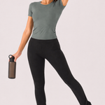 A woman wearing womens-black-kick-flare-leggings with high waist holding a water bottle in an active pose, styled with a green crop tee and headband