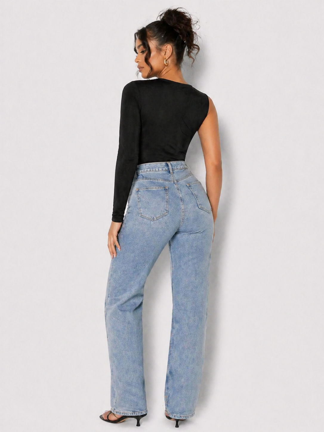 Full length back view of a woman in a Women's Black One Shoulder Long Sleeve Ruched Bodysuit with jeans