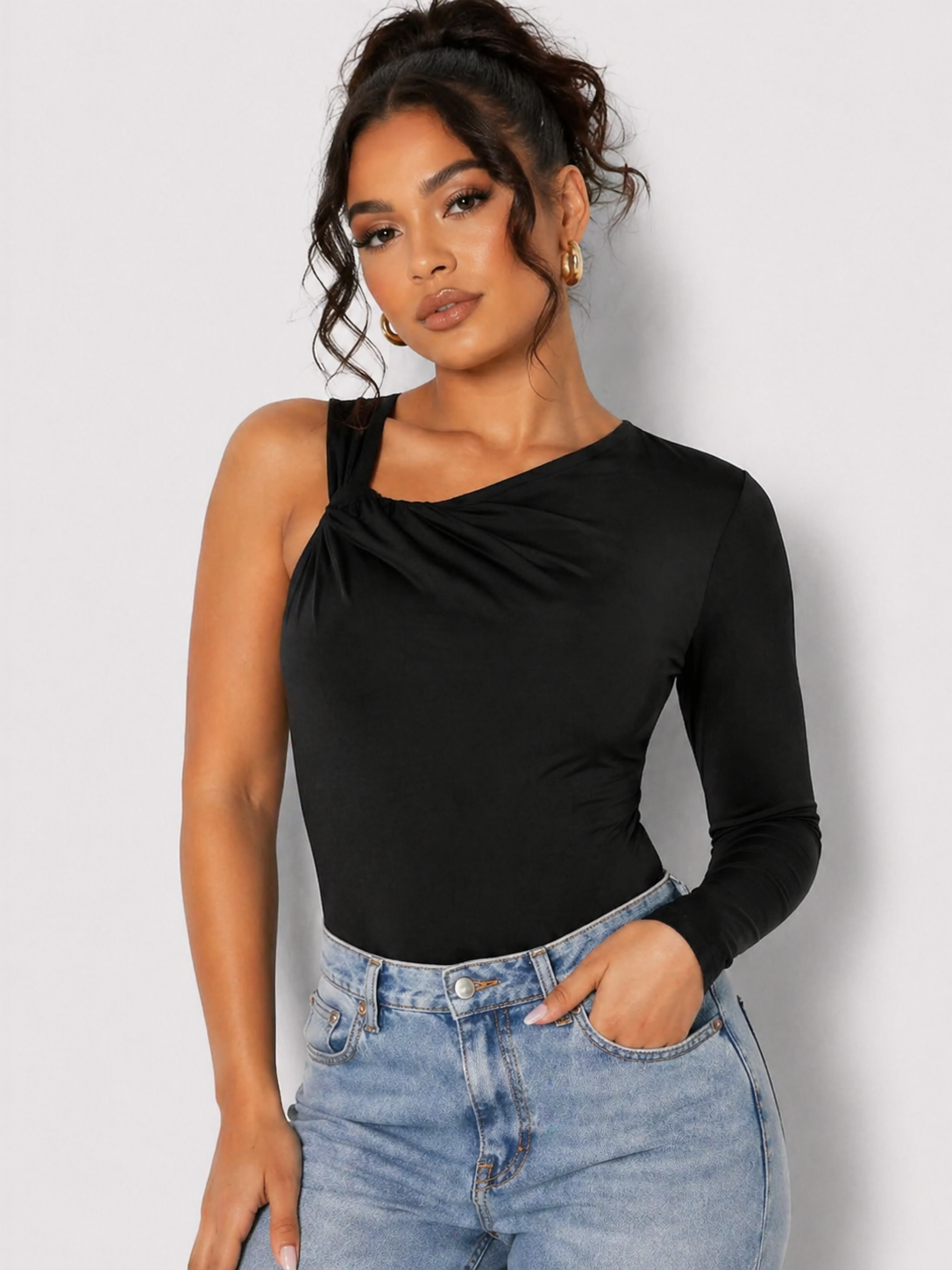 Front view of a woman wearing a Women's Black One Shoulder Ruched Slinky Bodysuit with blue jeans
