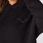 Detailed shot of the tonal embroidery on the chest of a black oversized hoodie