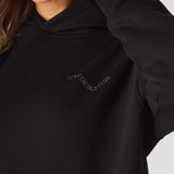 Detailed shot of the tonal embroidery on the chest of a black oversized hoodie