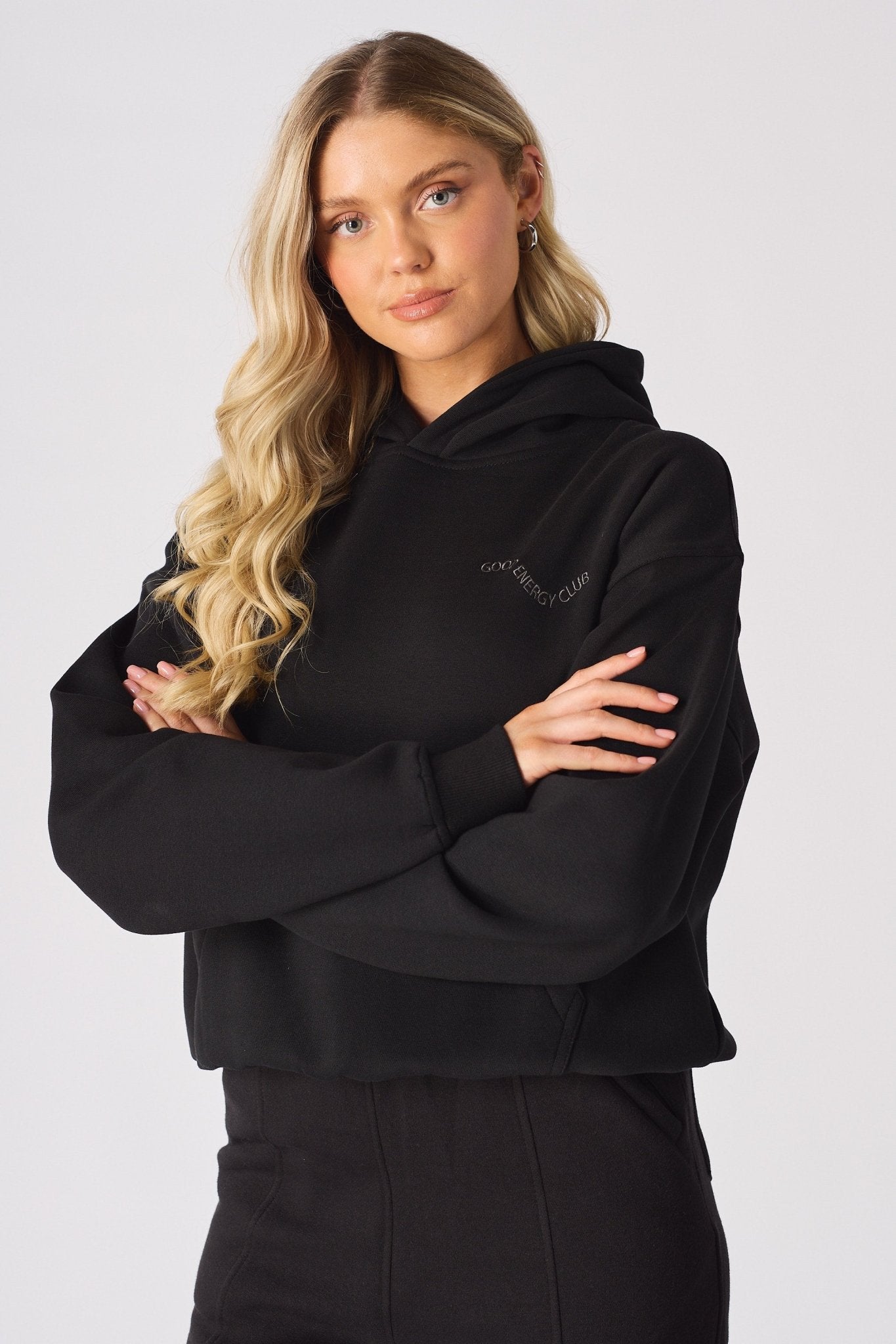 A model posing with arms crossed in a stylish black oversized hoodie