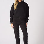 A woman wearing a black oversized hoodie with hands inside the front pocket