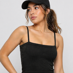 A woman wearing womens-black-ribbed-crop-top with thin cami straps and a black cap, front view
