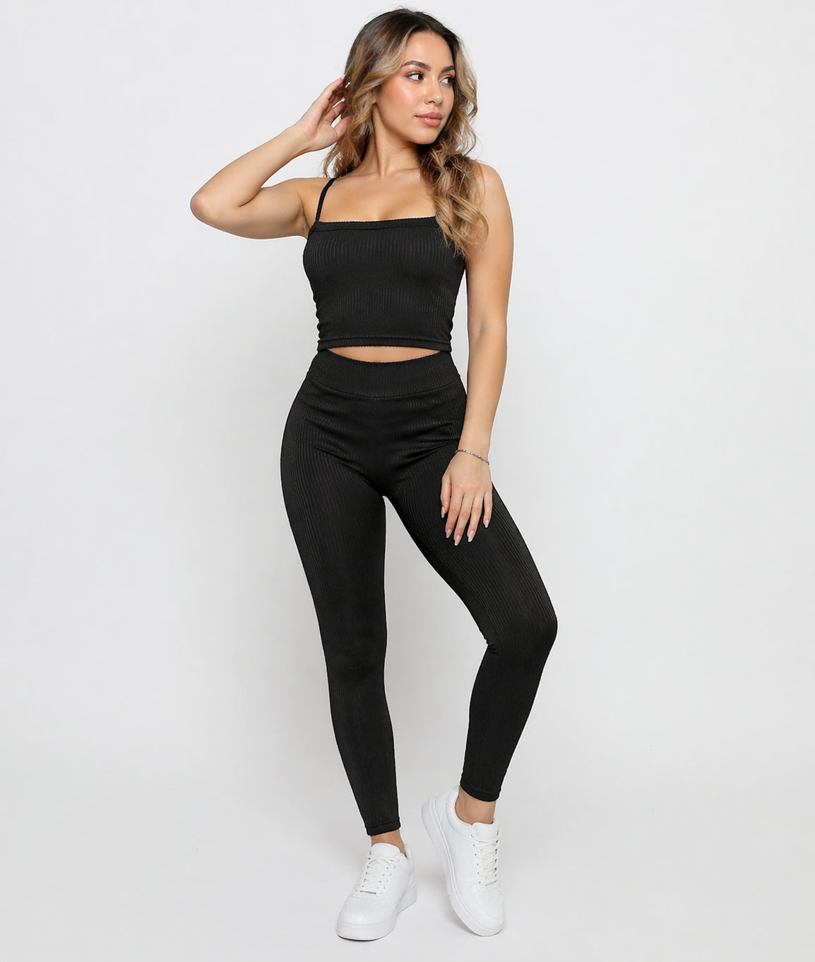 A woman standing wearing Women's Black Ribbed High Waist Leggings with matching cami crop top co-ord set full length view
