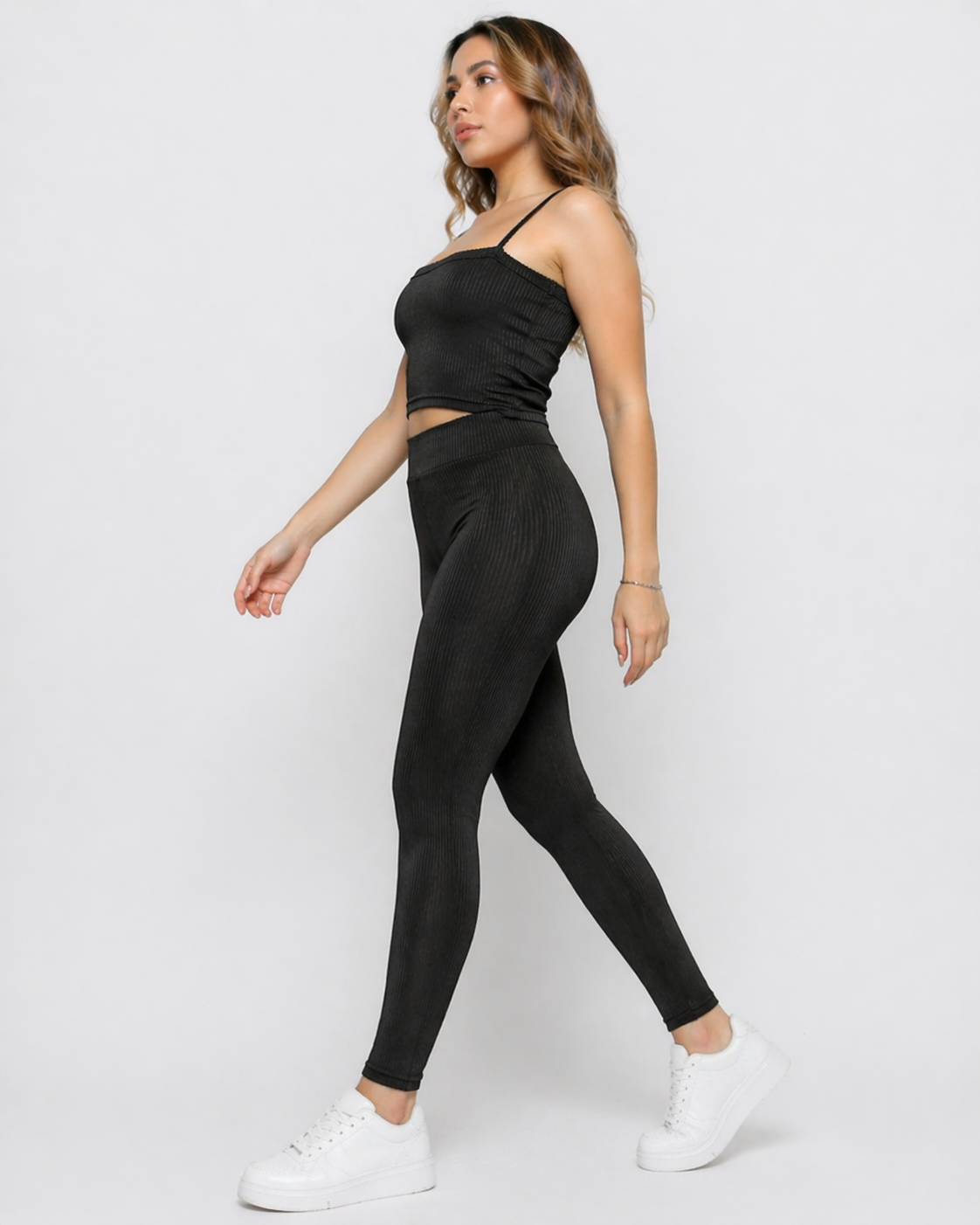 Side view of a woman walking in Women's Black Ribbed High Waist Leggings with co-ord cami crop top