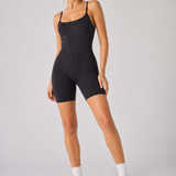 A woman wearing womens-black-strappy-unitard full length front view styled with white socks and white trainers
