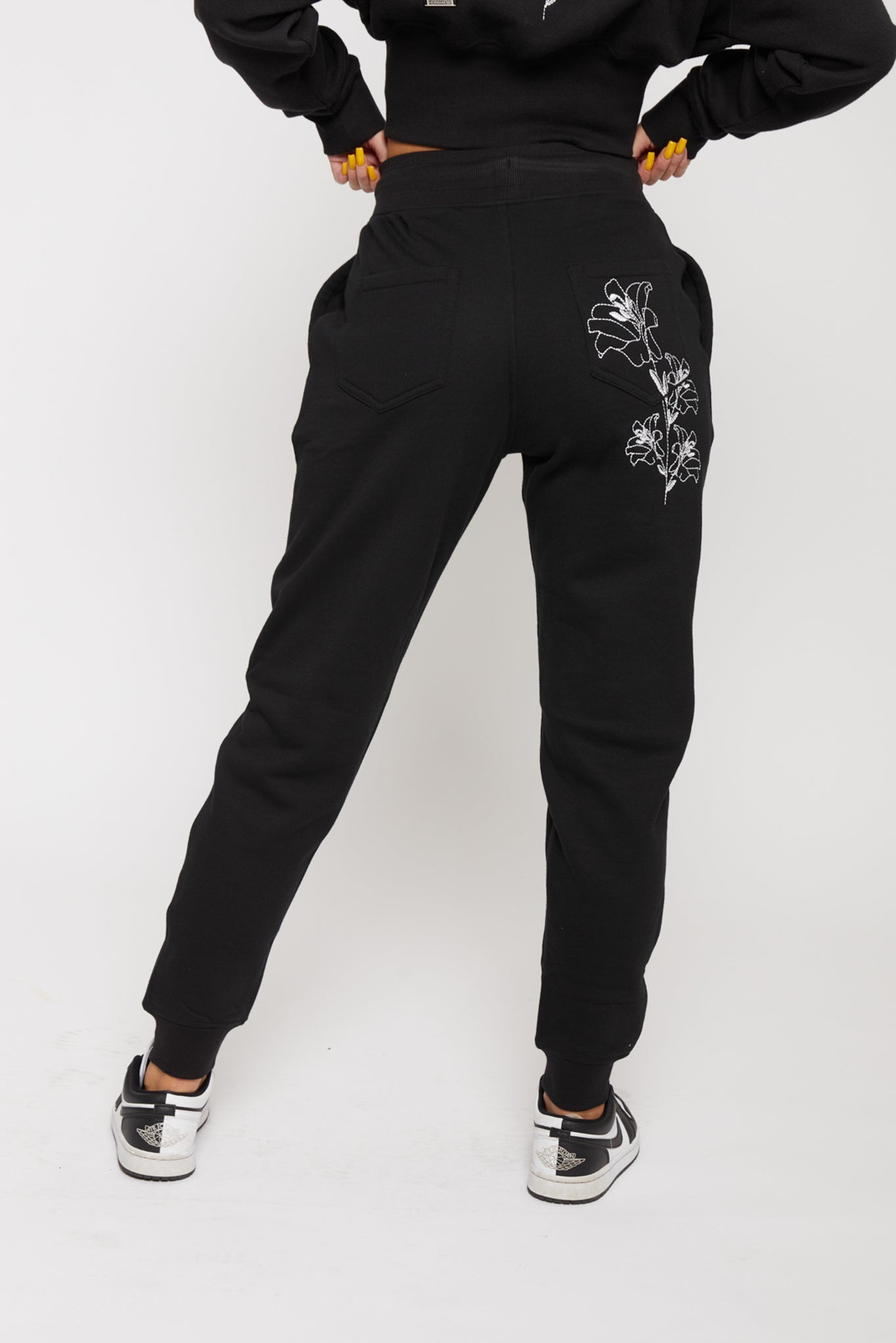 Back view of the women's black tapered joggers with white floral embroidery