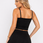 A woman showing the smocked back of a Women's Black Cami Crop Top with matching leggings