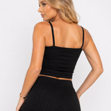 A woman showing the smocked back of a Women's Black Cami Crop Top with matching leggings