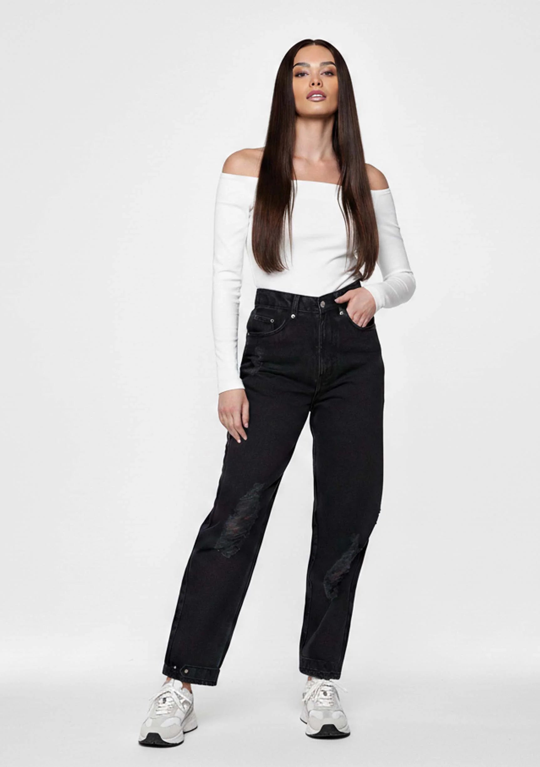 Front view of a model wearing Women's Black Wash Straight Leg Jeans with knee rips and ankle poppers