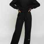 Full front view of a woman styling black wide leg joggers with a matching top