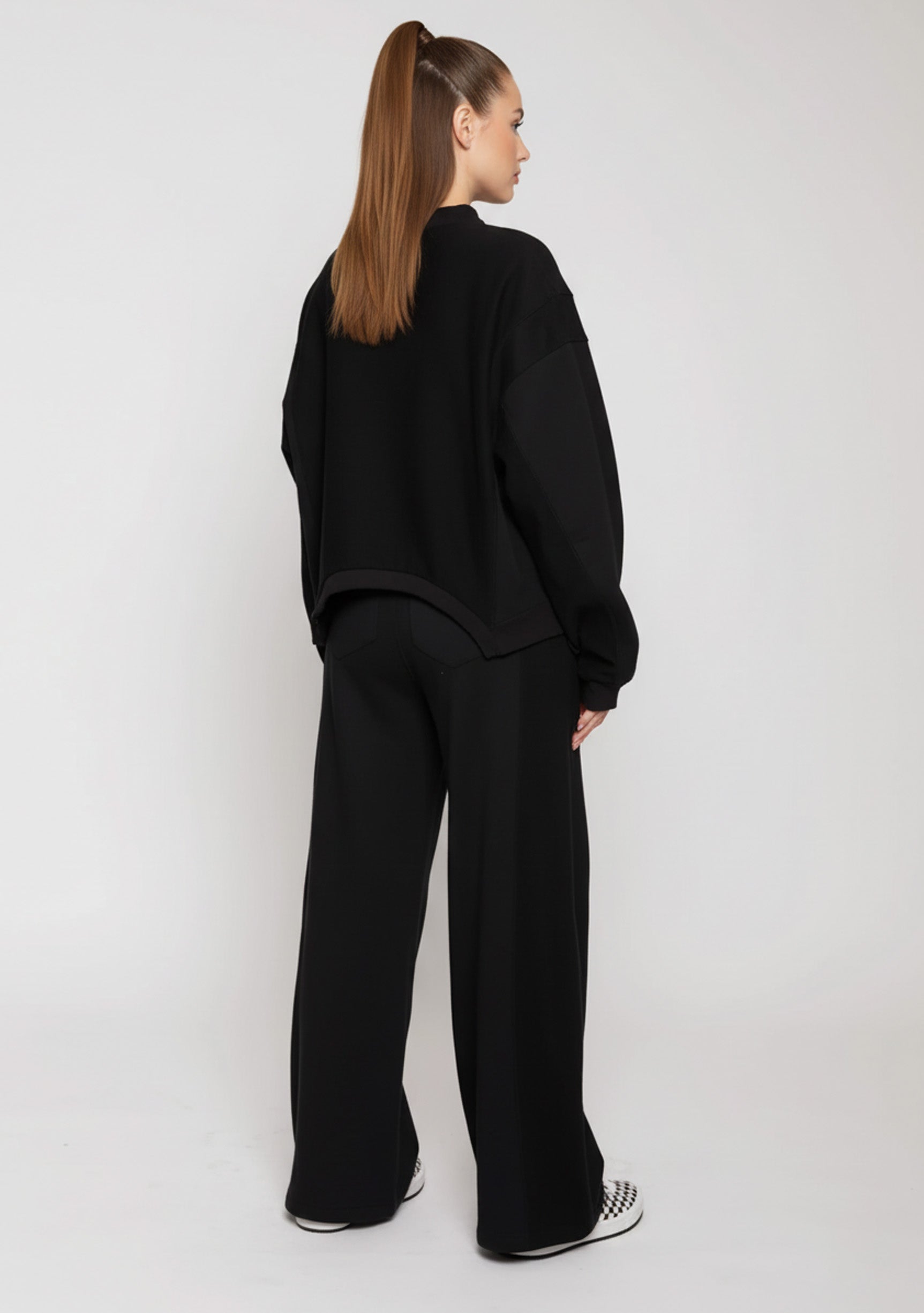 Side view of a woman wearing black wide leg joggers and a matching jumper