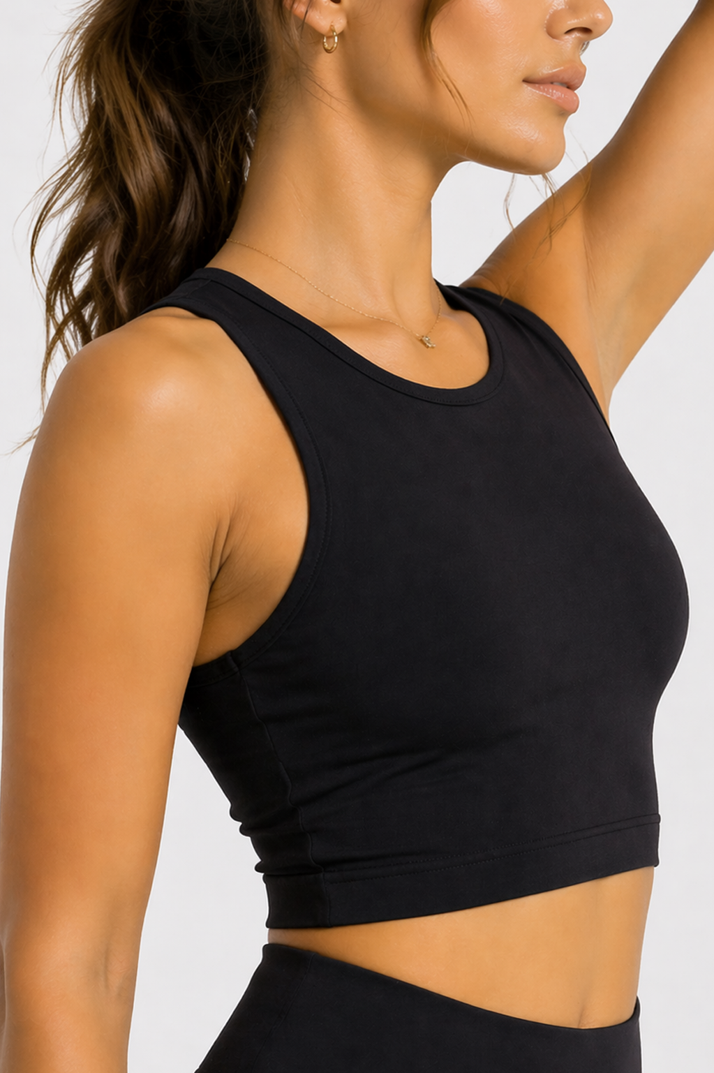 Side profile close-up of a women's black workout crop top showing the sleeveless racer neck fit.