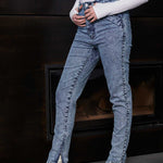 Side view of a model wearing women's blue acid wash jeans with an ankle zip