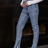 Side view of a model wearing women's blue acid wash jeans with an ankle zip