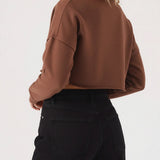 The rear view of a brown cropped jumper showing the relaxed fit and raw cut hemline