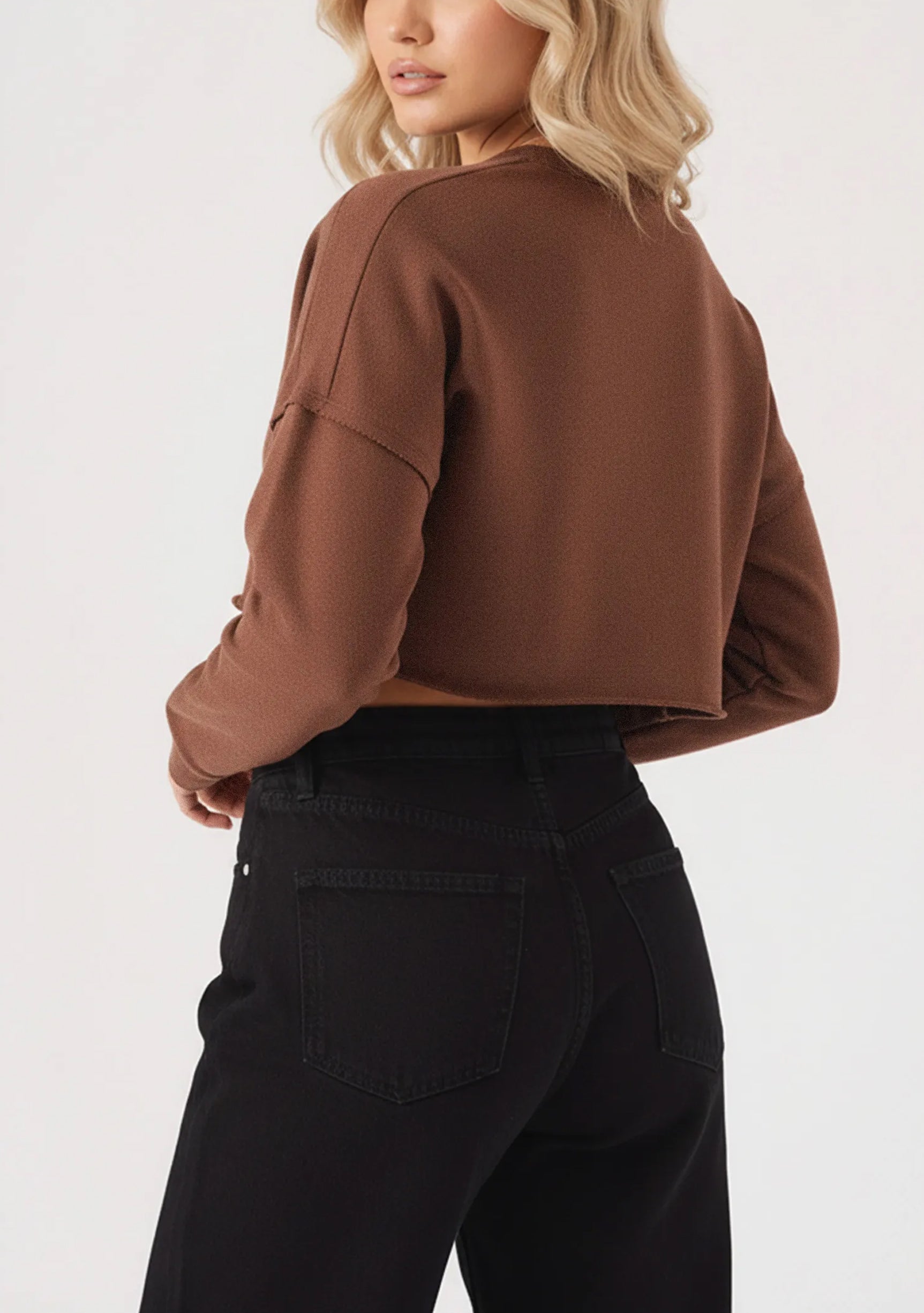 The rear view of a brown cropped jumper showing the relaxed fit and raw cut hemline