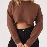 A front view of a blonde woman wearing a brown cropped jumper for women with black high waisted jeans