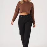 A full length front view of a model styling a brown cropped jumper with casual black trousers