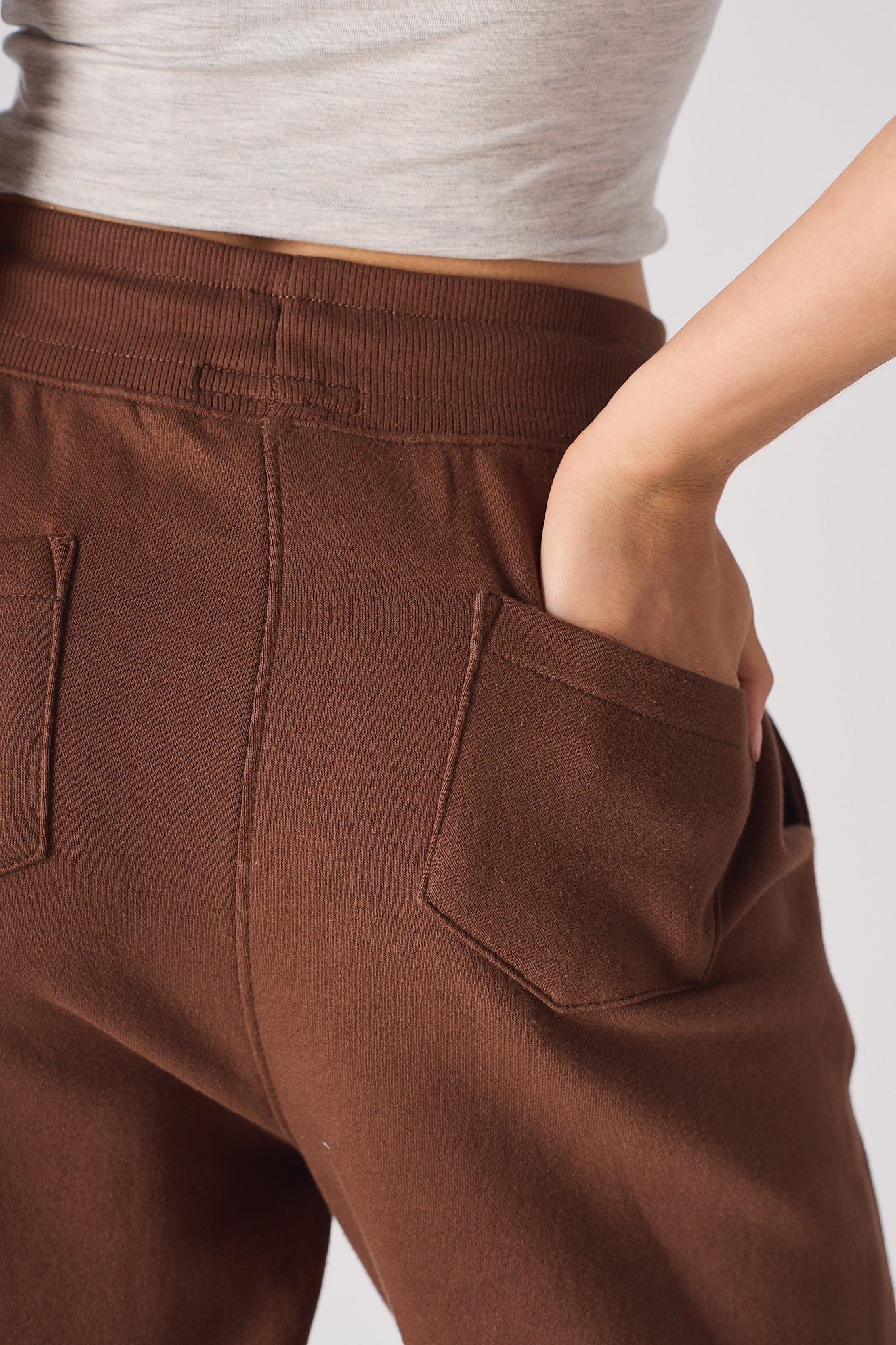 close up of back patch pocket and embroidery on brown tapered joggers