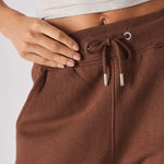 close up of elasticated waistband with drawstrings on brown tapered joggers
