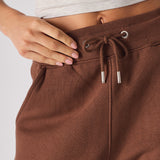 close up of elasticated waistband with drawstrings on brown tapered joggers