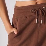 close up of hand in side pocket on brown tapered joggers