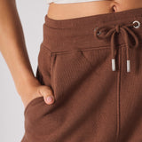 close up of hand in side pocket on brown tapered joggers